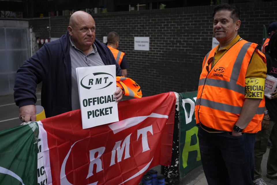 Workers and members of the RMT (The National Union of Rail, Maritime and Transport Workers) union stand on a picket line outside Euston train station, in London, during a railway workers strike, Thursday, June 23, 2022. Tens of thousands of railway workers walked off the job in Britain on Tuesday, bringing the train network to a crawl in the country's biggest transit strike for three decades. Britain faces the second of three national railway strikes Thursday after new negotiations between union and employers ended in deadlock. (AP Photo/Matt Dunham)