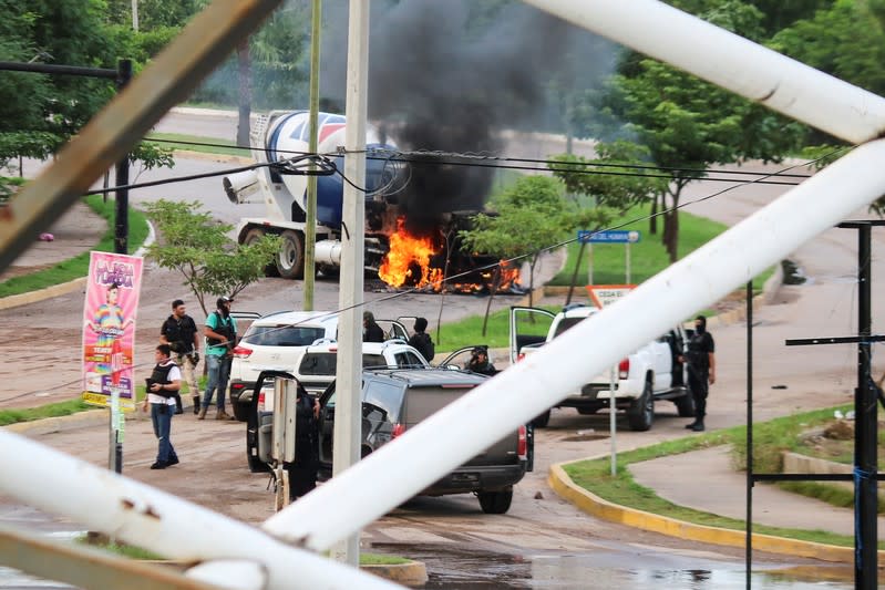 Cartel gunmen are seen near a burning truck during clashes with federal forces following the detention of Ovidio Guzman, son of drug kingpin Joaquin "El Chapo" Guzman, in Culiacan