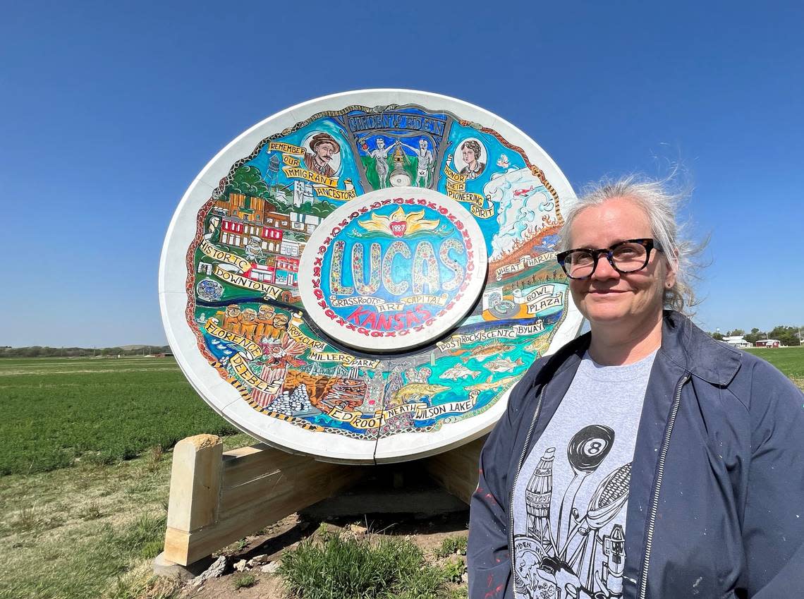 Artist Erika Nelson stands in front of her own colossal creation: The World’s Largest Souvenir Travel Plate in Lucas.