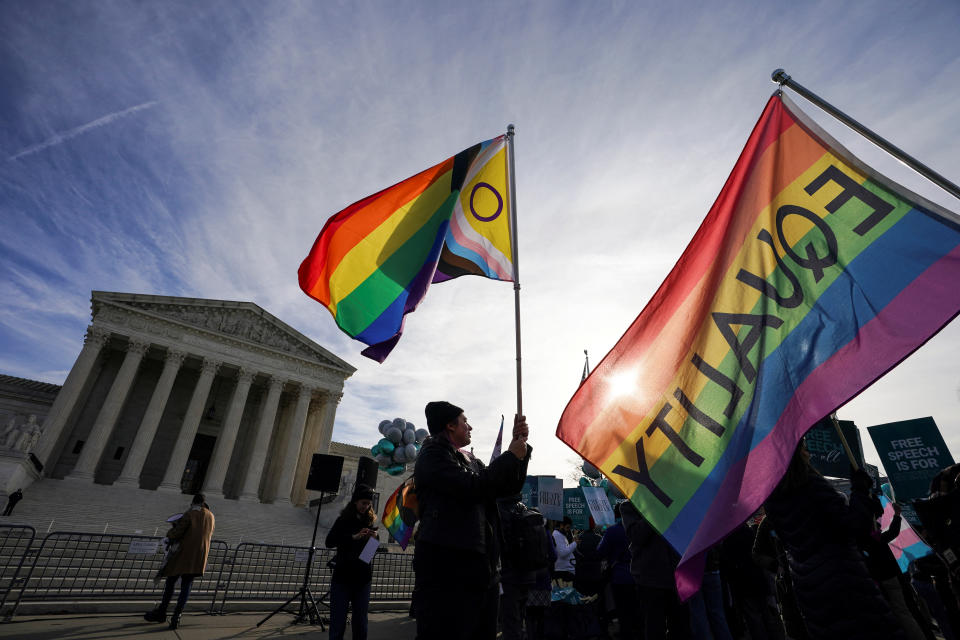 Protesters hold LGBT rights rainbow (pride) flags as activists gather outside the U.S. Supreme Court, where justices were set to hear arguments in a major case pitting LGBT rights against a claim that the constitutional right to free speech exempts artists from anti-discrimination laws in a dispute involving an evangelical Christian web designer who refuses to provide her services for same-sex marriages, in Washington, U.S., December 5, 2022. REUTERS/Kevin Lamarque