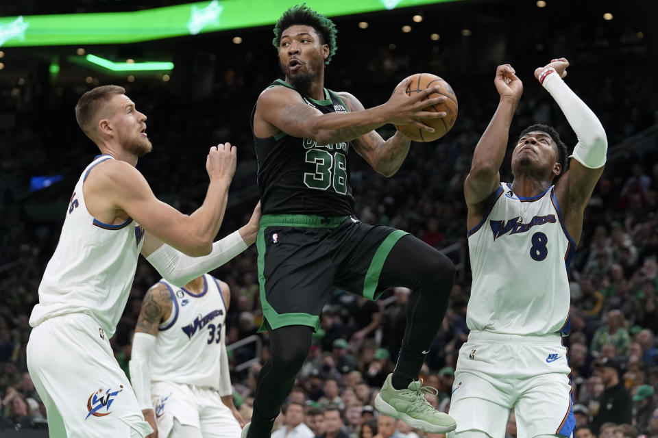 FILE - Boston Celtics guard Marcus Smart, center, looks to pass past Washington Wizards center Kristaps Porzingis, left, and forward Rui Hachimura, right, during the first half of an NBA basketball game Oct. 30, 2022, in Boston. A person with knowledge of the deal says the Wizards have agreed to trade Porzingis to the Celtics. The person spoke to The Associated Press on condition of anonymity because the agreement hadn’t been announced. The trade comes with Porzingis accepting his player option for next season. ESPN reports the deal also includes the Memphis Grizzlies who are acquiring Smart from Boston in exchange for first-round draft picks in 2023 and 2024. (AP Photo/Steven Senne, File)