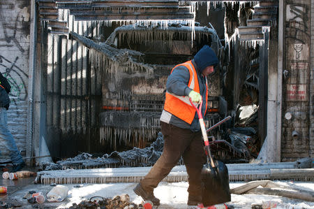 A worker cleans up after a large fire extinguished by the New York Fire Department (NYFD) as they worked in frigid conditions in the Brooklyn Borough of New York, U.S., January 31, 2019. REUTERS/Lloyd Mitchell