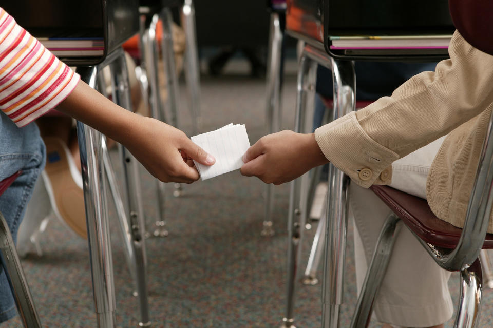 Stock image close up of two kids passing a note in class
