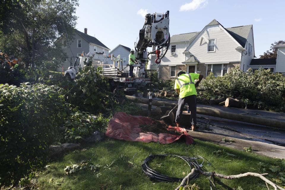 A utility crew works amongst fallen trees in a residential neighborhood, Friday, Aug. 18, 2023, in Johnston, R.I., after severe weather swept through the area. (AP Photo/Michael Dwyer)