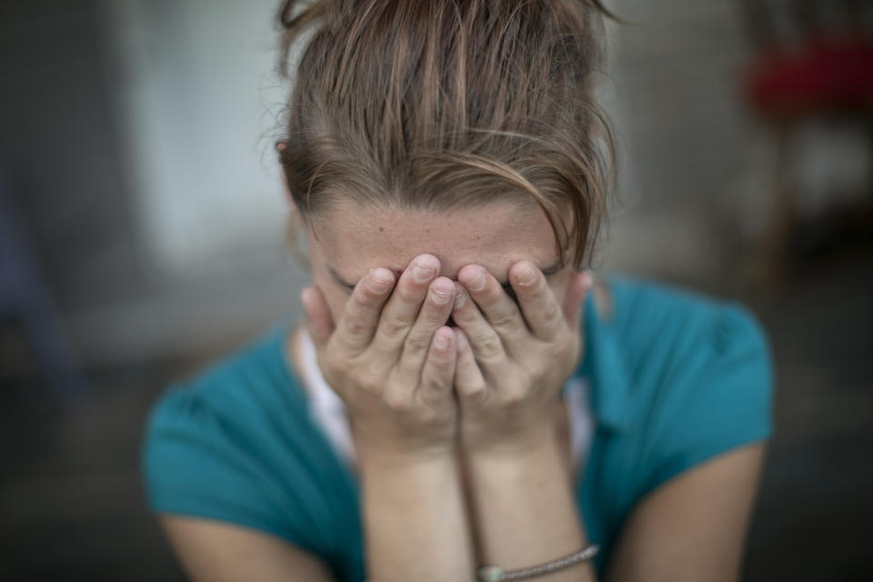 Tasha Lamm, 30, covers her face, becoming self-conscious while posing for a portrait, in Bidwell, Ohio, on Monday, July 27, 2020. Lamm dreams of taking her family and leaving Ohio, the scene of so much personal pain. "I'm ready to leave this hellhole and everyone in it because I know there's something better for me." (AP Photo/Wong Maye-E)