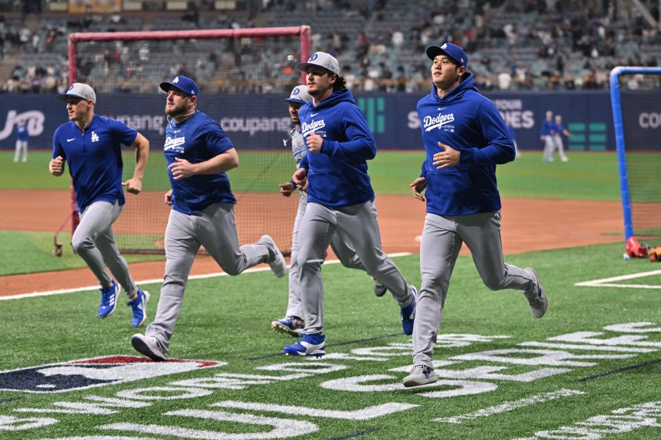 Los Angeles Dodgers' Shohei Ohtani (right) warms up during practice at the Gocheok Sky Dome in Seoul on March 20, 2024, ahead of the 2024 MLB Seoul Series baseball game between Los Angeles Dodgers and San Diego Padres.