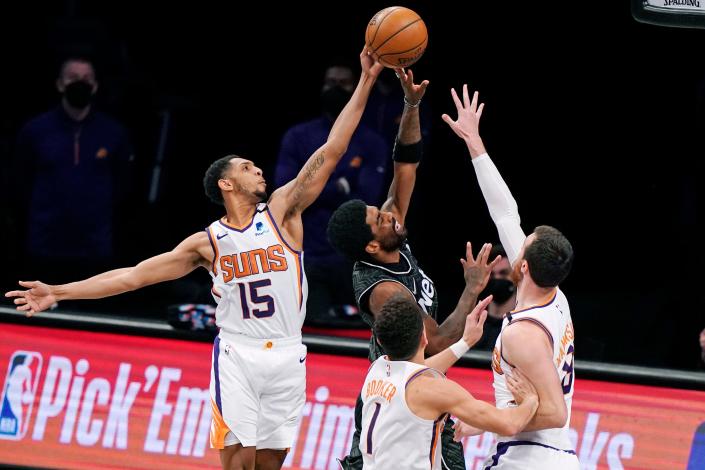 Phoenix Suns guards Cameron Payne (15), and Devin Booker (1) pair up with Suns forward Frank Kaminsky (8) as they triple team Brooklyn Nets guard Kyrie Irving (11) during the second quarter of an NBA basketball game, Sunday, April 25, 2021, in New York. (AP Photo/Kathy Willens)