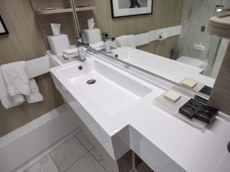 a bathroom with a sink, shelves, and towels