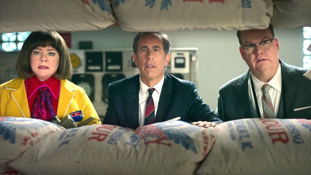  Melissa McCarthy as Donna Stankowski, Jerry Seinfeld as Bob Cabana and Jim Gaffigan as Edsel Kellogg III hide behind bags of flour in the Netflix movie Unfrosted. 