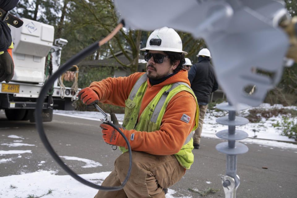 A worker from PG&E works on installing a new power line as crews work on restoring power to the area after a storm on Tuesday, Jan. 16, 2024, in Lake Oswego, Ore. (AP Photo/Jenny Kane)