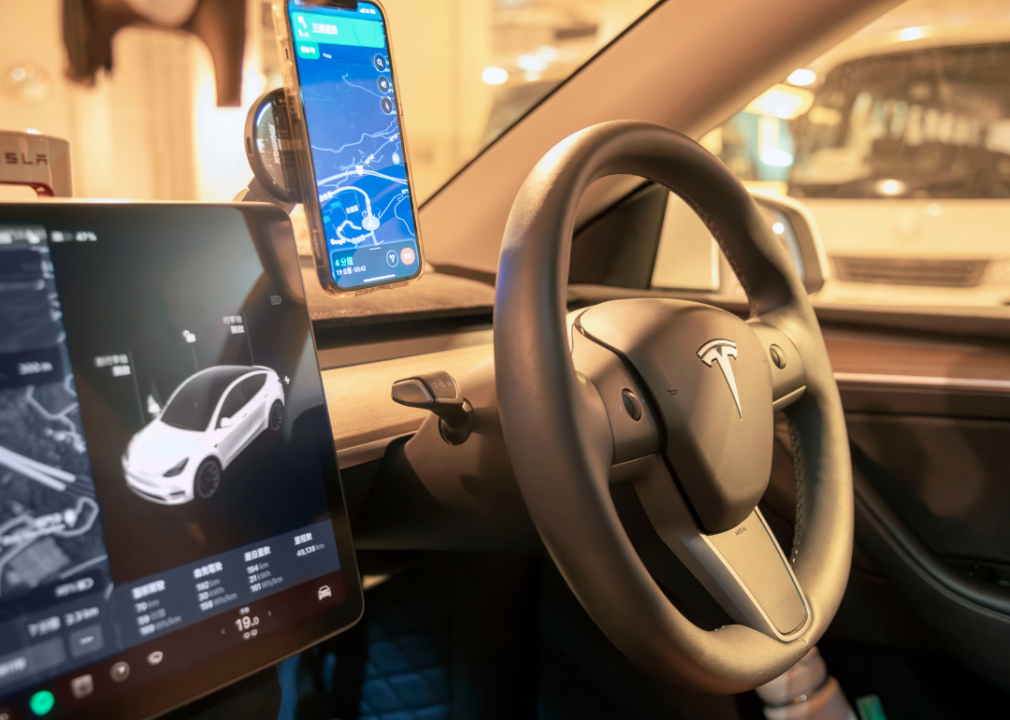 The inside of a Tesla car with a phone GPS map attached to the dash.