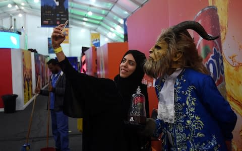 Saudi woman takes a selfie with a man dressed as Beast from Disney film Beauty and the Beast at the country's first ever Comic-Con Arabia event