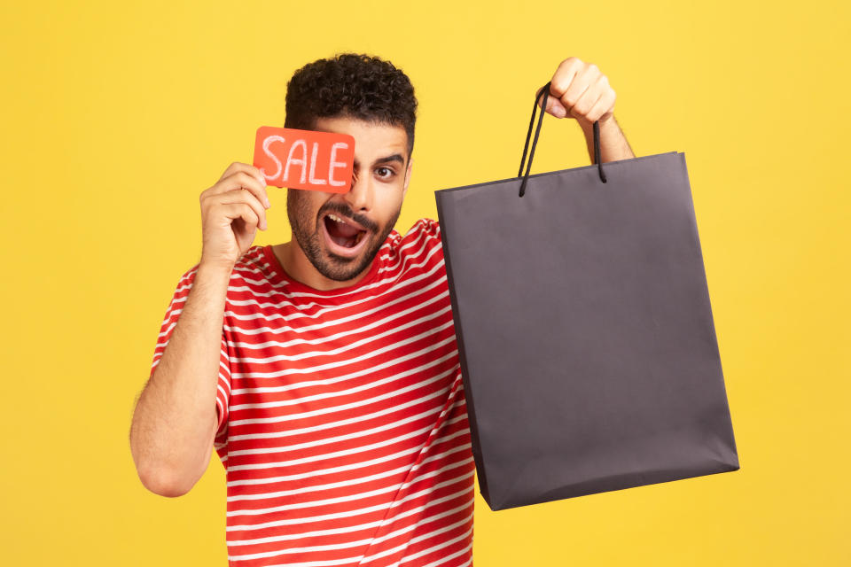 Man holding a sale card and black paper bag, illustrating a story on Amazon's Black Friday sale. 