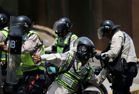 A riot police officer throws a tear gas grenade as demonstrators rally against Venezuela's President Nicolas Maduro's government in Caracas, Venezuela April 10, 2017. REUTERS/Carlos Garcia Rawlins