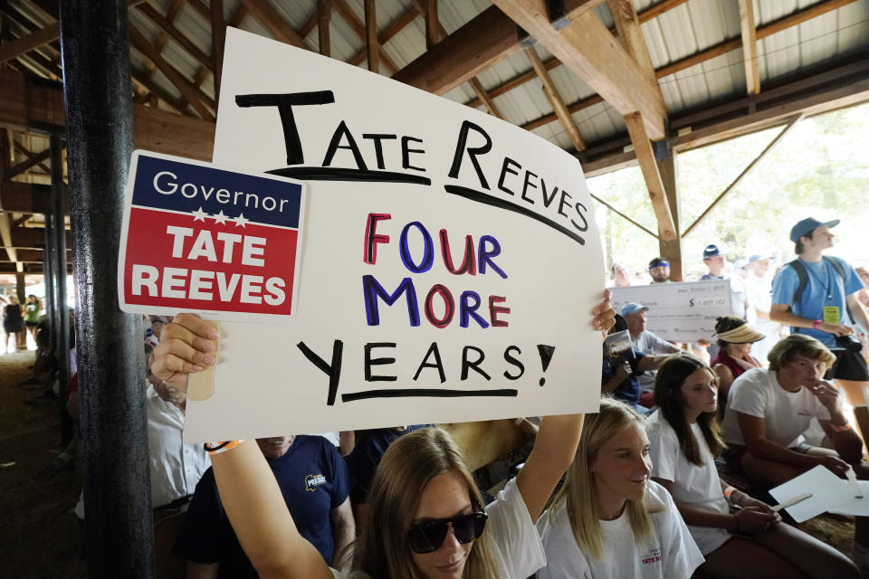 A supporter of Mississippi Republican Gov. Tate Reeves waves a homemade poster while holding onto a small fan during his campaign speech before a crowd at the Neshoba County Fair in Philadelphia, Miss., Thursday, July 27, 2023. Reeves faces two opponents in the party primary Aug. 8, as he seeks reelection. (AP Photo/Rogelio V. Solis)
