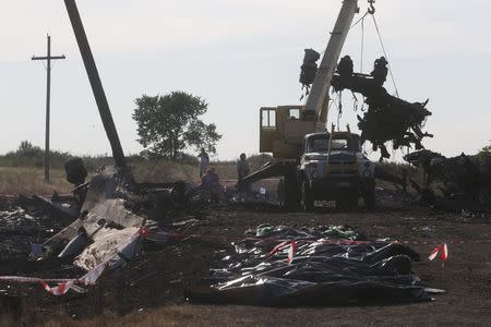 A crane moves wreckage at the crash site of Malaysia Airlines Flight MH17 in front of body bags near the village of Hrabove, Donetsk region, July 20, 2014. REUTERS/Maxim Zmeyev
