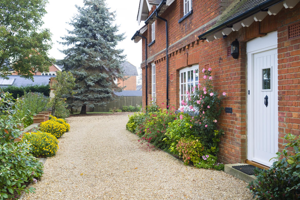 English country house and garden in Autumn with a gravel driveway. The house is Victorian period, with flower borders filled with shrubs and perennials