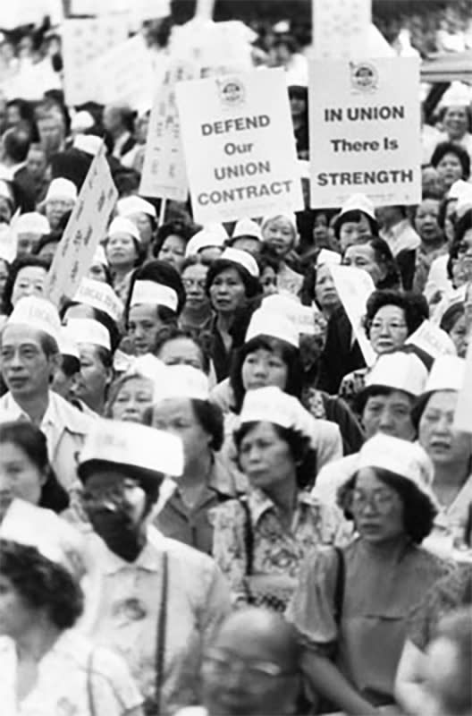 Members of ILGWU Local 23-25 hold signs showing their support for the union contract during the Chinatown Rally in Columbus Park, New York. Rallies took place on June 24, 1982 and July 15, 1982. (Courtesy of The Kheel Center ILGWU Collection, Cornell University)