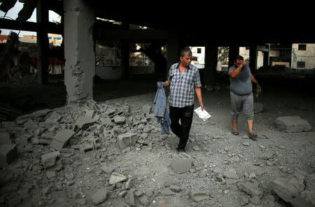 Palestinians inspect a building that was destroyed by Israeli air strikes in Gaza City, July 15, 2018. REUTERS/Suhaib Salem