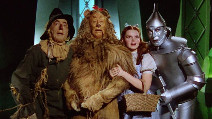 The characters from The Wizard of Oz holding each other close and looking at something off-screen.
