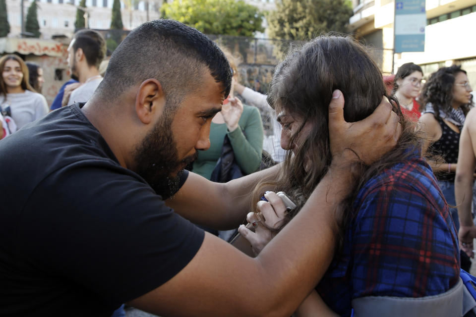 An anti-government protester calms another who was overwhelmed with tears after Lebanon Prime Minister Saad Hariri announced he is submitting his resignation, meeting one of the protesters' main demands, in front of the government palace in Beirut, Lebanon, Tuesday, Oct. 29, 2019. The protests have been on the streets for 13 days, calling for the government to resign and accusing longtime politicians of corruption. (AP Photo/Bilal Hussein)