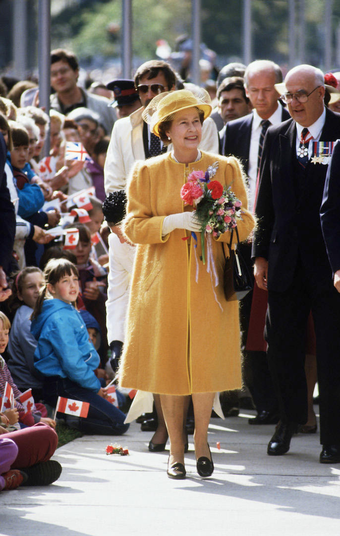 For a walkabout in Queen's Park, Her Majesty stood out from the crowd in a punchy yellow mohair coat and co-ordinating hat. <em>[Photo: Getty]</em>