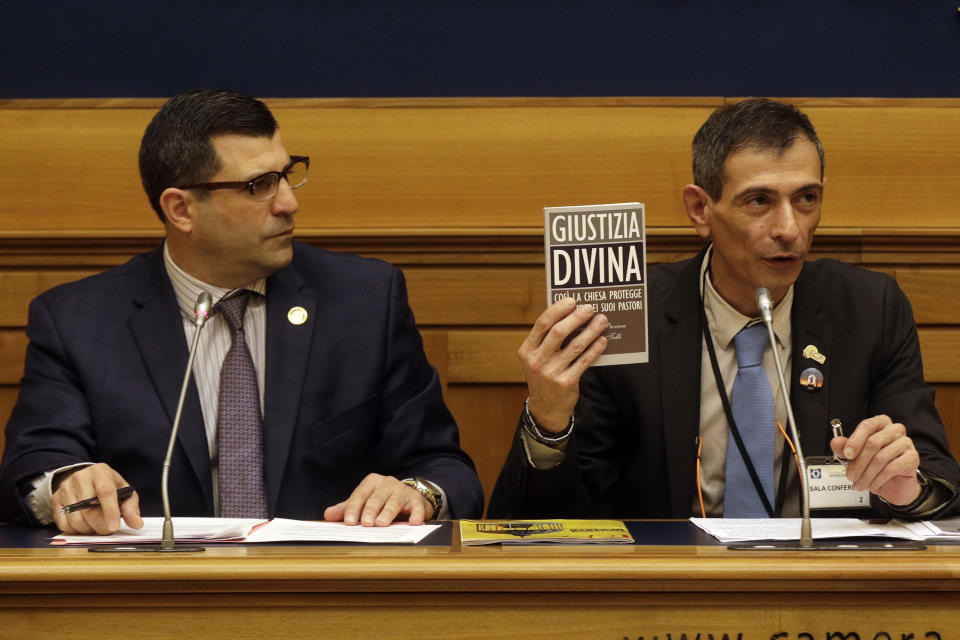 Survivor of sex abuse Francesco Zanardi, right, flanked by Mark Rozzi, Democratic member of the Pennsylvania House of Representatives, holds a book titled Divine Justice, reporting on how the Vatican covers up cases of priests who sexually abused, during a press conference at the Italian Lower Chamber press hall in Rome, Thursday, Feb. 21, 2019. Pope Francis opened a landmark sex abuse prevention summit Thursday by warning senior Catholic figures that the faithful are demanding concrete action against predator priests and not just words of condemnation. (AP Photo/Gregorio Borgia)