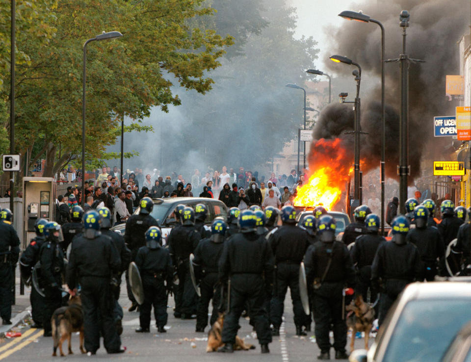 Flames sparked as riot police face crowded protesters in Hackney Monday night.