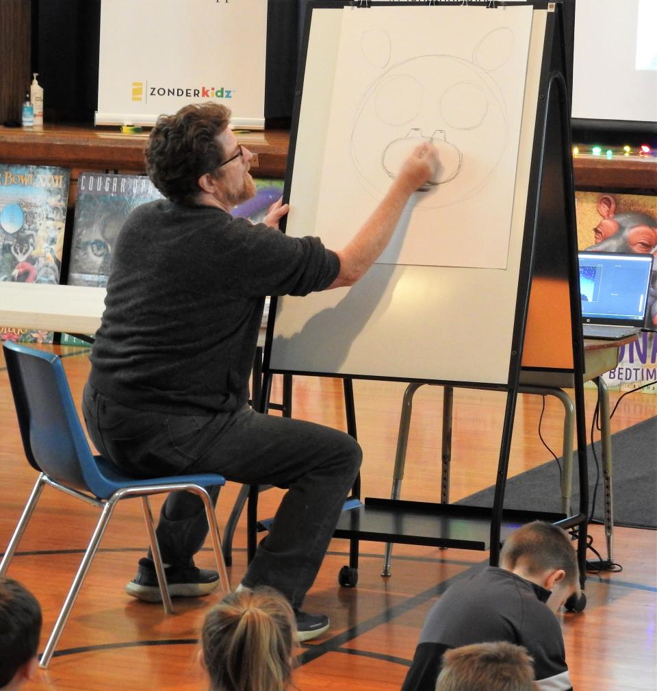 Richard Cowdrey of Mount Vernon walks students at Conesville Elementary School through how to draw Fiona the hippo during a presentation Wednesday. This was part of special events and programs commemorating the short week before Christmas for students.