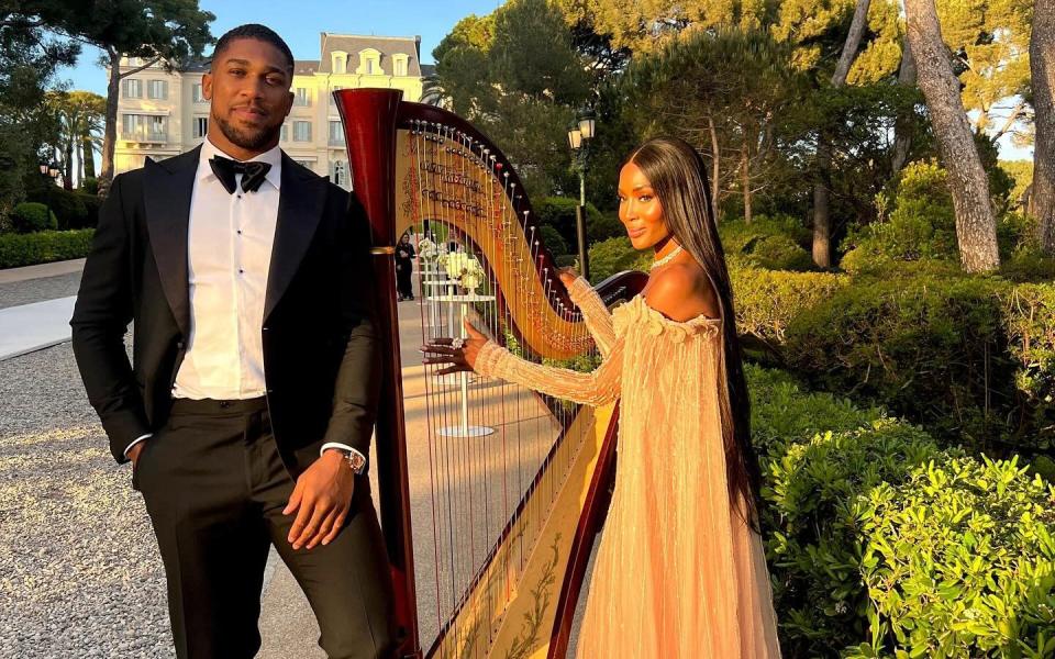 Mr Joshua wears black tie and Ms Campbell pretends to play a harp