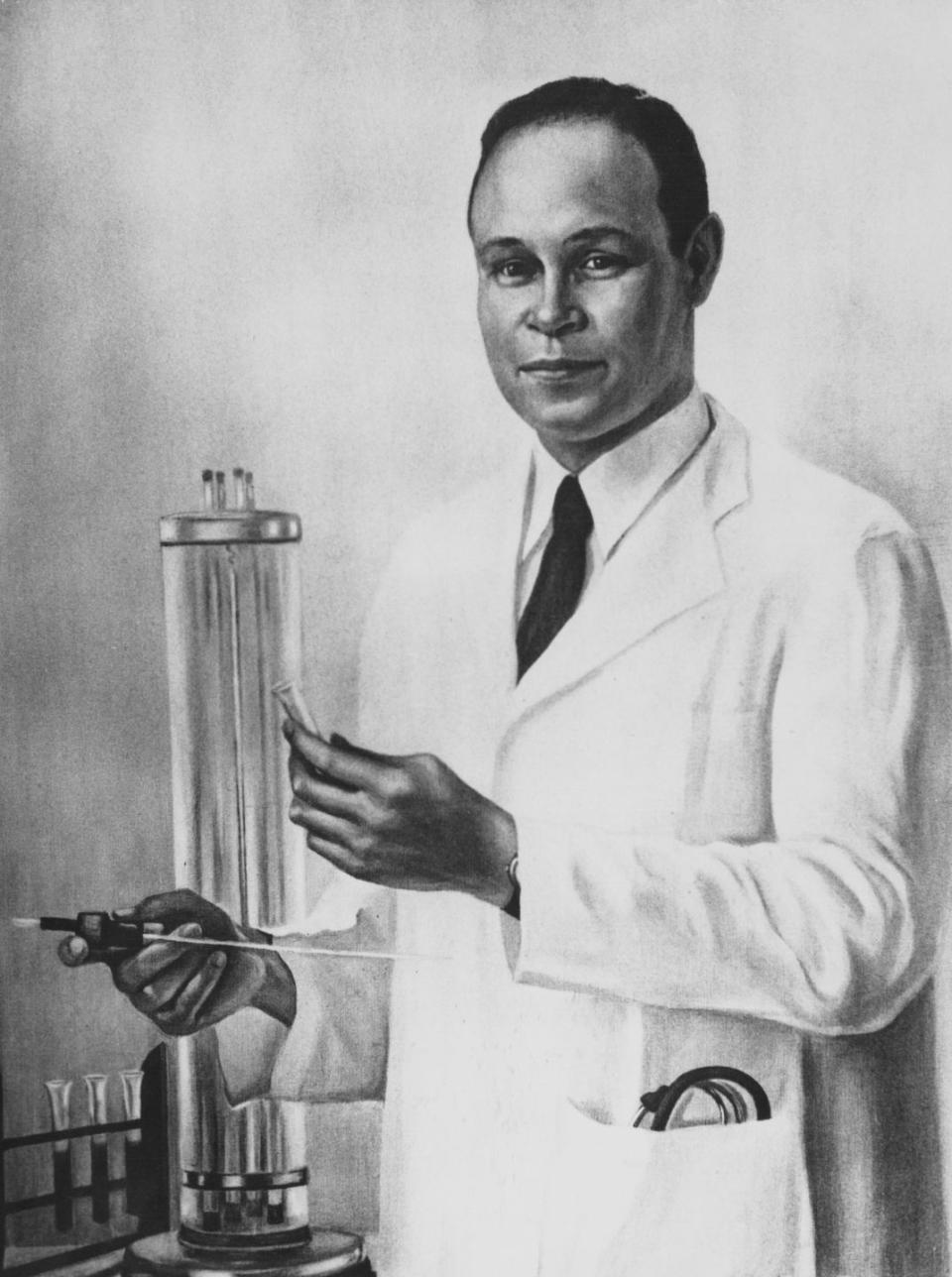 charles drew looks directly forward, wearing a lab coat and standing next to laboratory equipment