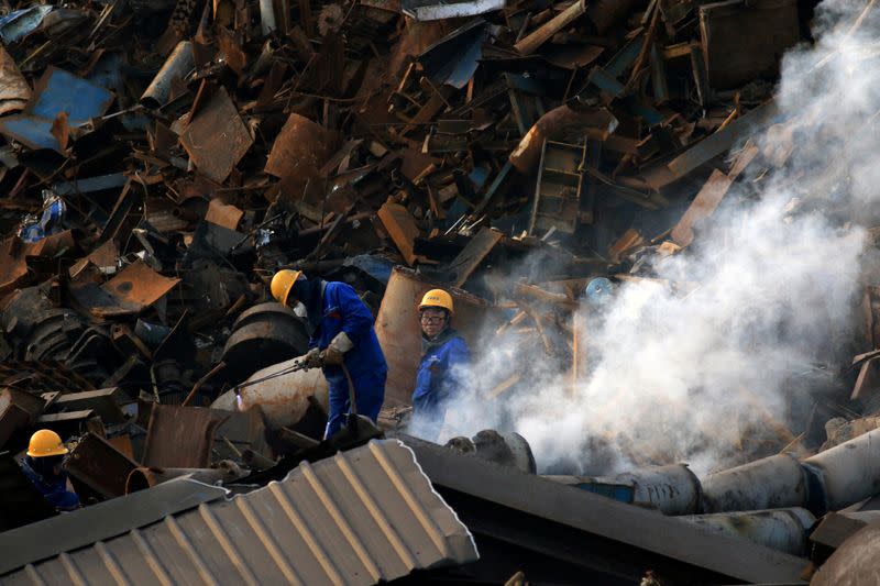 FILE PHOTO: Workers dismantle scrap metal at a steel plant in Huaian
