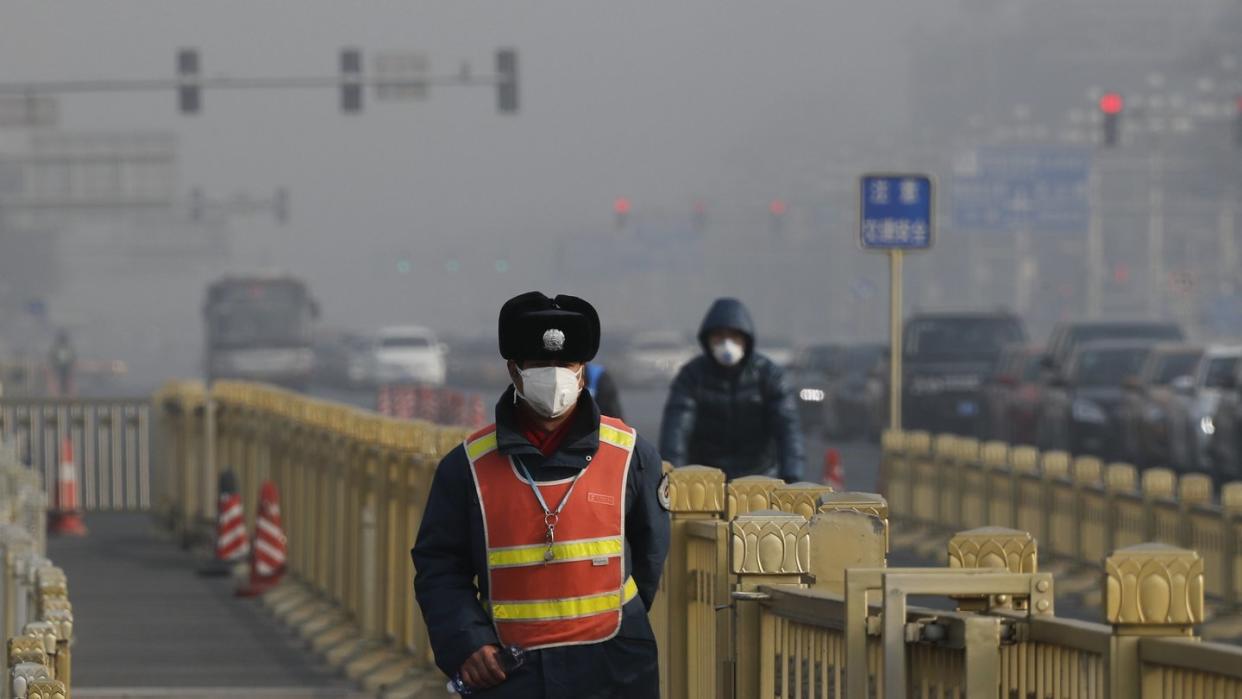 Ein Verkehrspolizist mit Maske steht in der Nähe des Tiananmen-Platzes in Peking, während dichter Smog die Sicht trübt. Foto: Andy Wong/AP