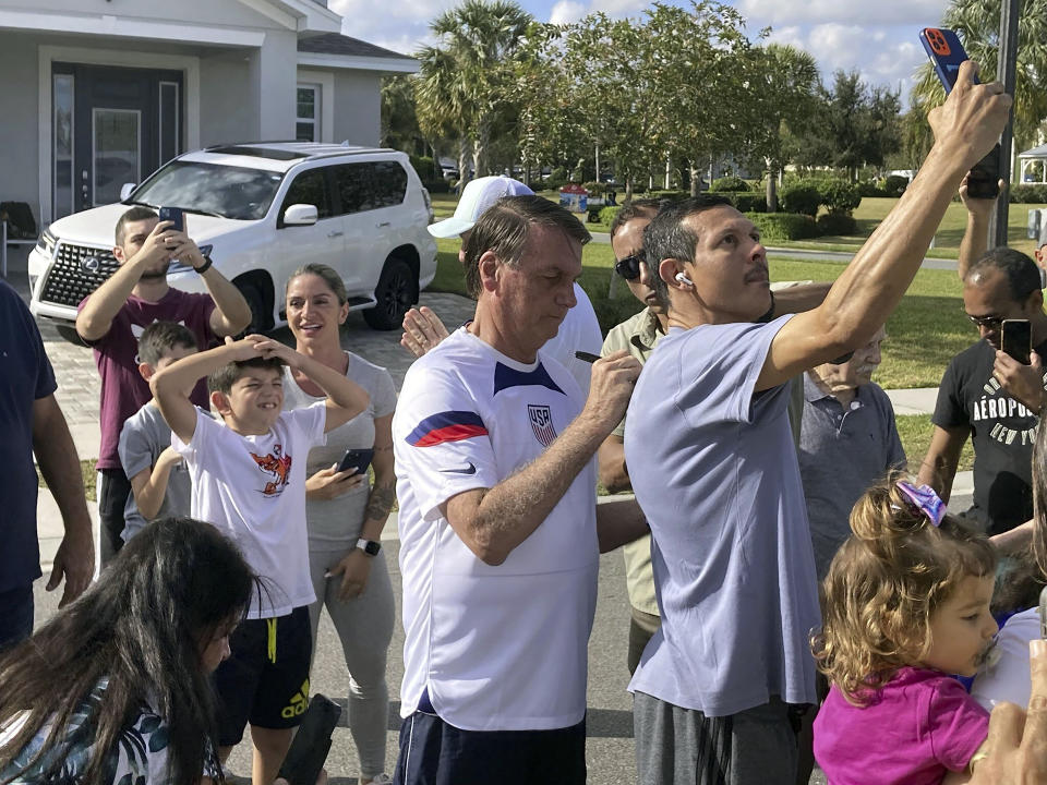 Former Brazil President Jair Bolsonaro, center, meets with supporters outside a vacation home where he is staying near Orlando, Fla., on Wednesday, Jan. 4, 2023. (Skyler Swisher/Orlando Sentinel via AP)