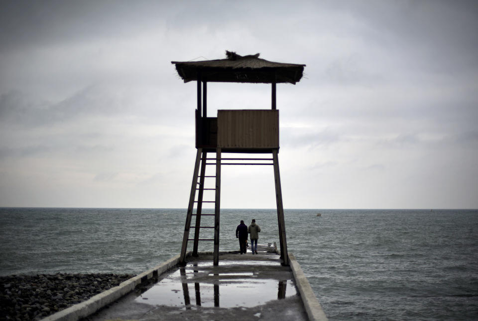 Beach goers walk out on a boardwalk pier along the Black Sea, Wednesday, Jan. 29, 2014, in Sochi, Russia, home of the upcoming 2014 Winter Olympics. (AP Photo/David Goldman)