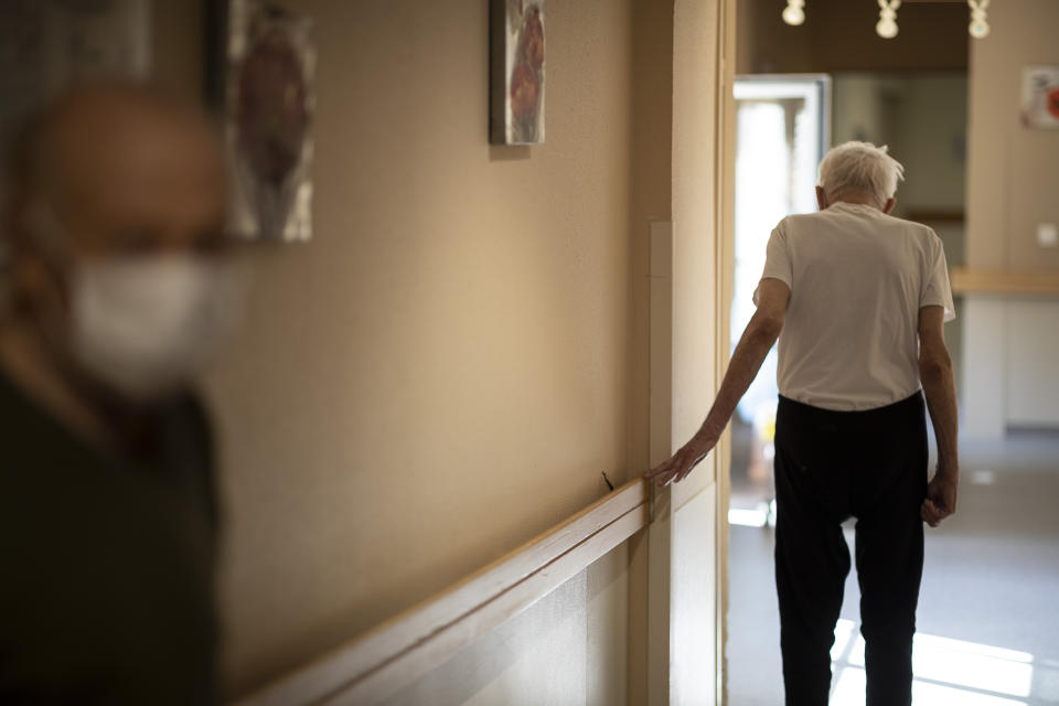 Richard Eberhardt walks along a corridor at a nursing home in Kaysesberg, France Thursday April 16, 2020. The elderly make up a disproportional share of coronavirus victims globally, and that is especially true in nursing homes, which have seen a horrific number of deaths around the world. (AP Photo/Jean-Francois Badias)