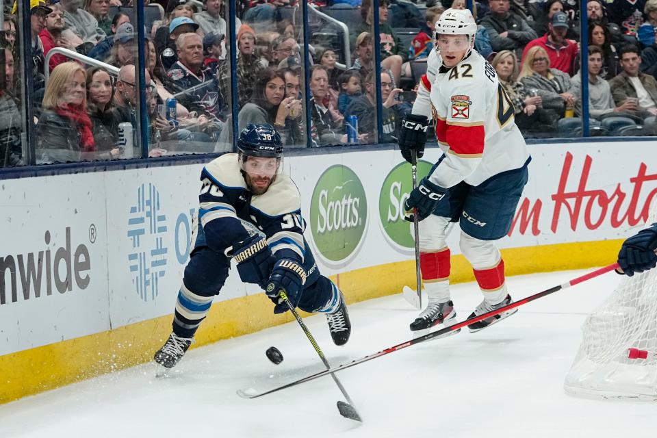 Columbus Blue Jackets center Boone Jenner (38) reaches for a puck in front of Florida Panthers defenseman Gustav Forsling (42) during the first period of the NHL hockey game at Nationwide Arena on April 1, 2023.