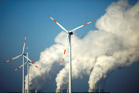 Steam billows from the cooling towers of Vattenfall's Jaenschwalde brown coal power station behind wind turbines near Cottbus, Germany, December 2, 2009. REUTERS/Pawel Kopczynski/File Photo