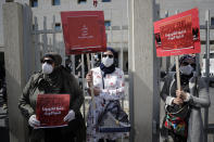 Anti-government protesters hold up banners in Arabic that read, "You are the coronavirus, you are the epidemic, (right) and Humiliation, bankruptcy, looting, starving and killing the rest of us, (center)," during ongoing protests against the Lebanese government in front of the Lebanese Ministry of Health, in Beirut, Lebanon, Wednesday, Feb. 26, 2020. (AP Photo/Hassan Ammar)