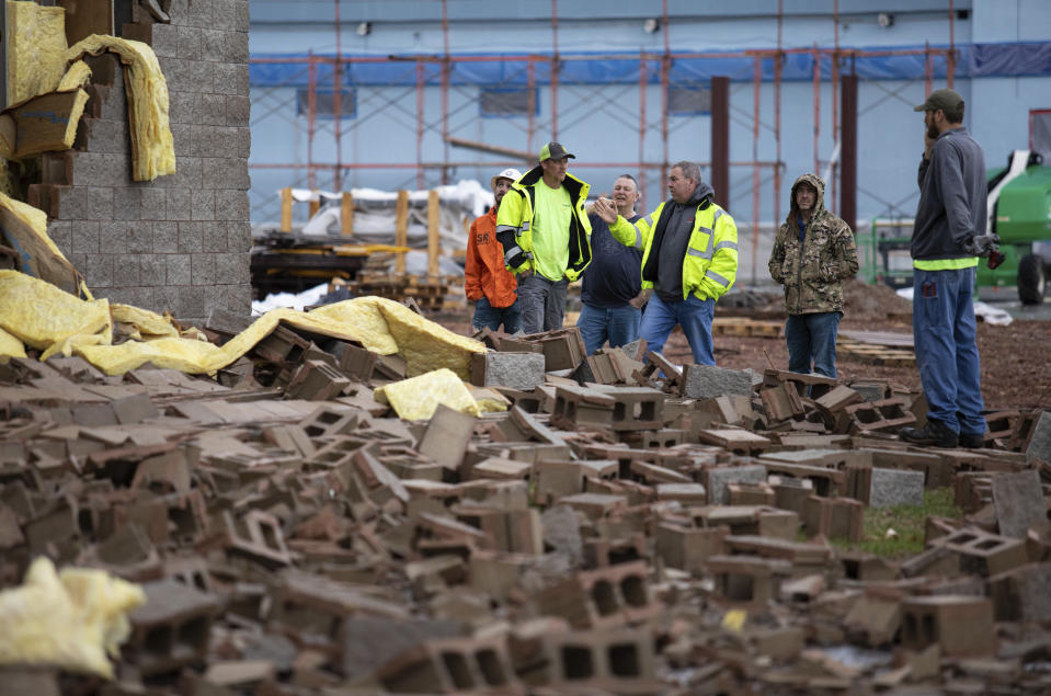 Stewart Richey Electrical employees and other utility workers and city crews survey and help clear debris at Thornton Furniture on Cave Mill Road in Bowling Green, Ky., after another tornado warning was issued, Saturday, Jan. 1, 2022, for Warren and surrounding counties, following the devastating tornadoes that tore through town on Dec. 11, 2021. Though the damage from Saturday's storm proved less catastrophic than the system that passed through in December, heavy rain and strong winds battered the area, causing damage along Cave Mill Road and the surrounding area. (Grace Ramey/Daily News via AP)