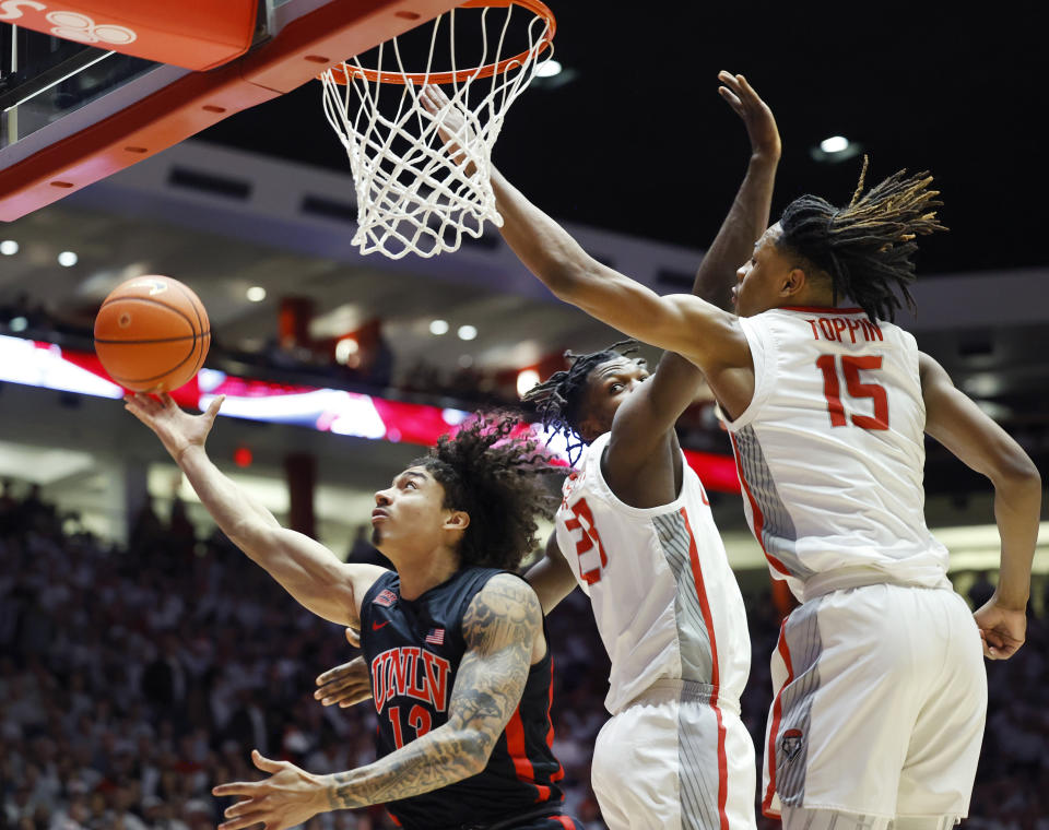 UNLV guard Brooklyn Hicks shoots and scores past the defense of New Mexico forward JT Toppin and New Mexico center Nelly Junior Joseph during the first half of an NCAA college basketball game, Saturday, Feb. 10, 2024, in Albuquerque, N.M. (AP Photo/Eric Draper)