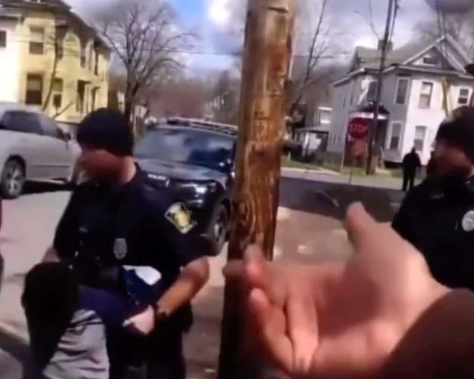 Syracuse police officers restrain an 8-year-old boy suspected of stealing a bag of chips. They placed the child in a patrol car, according to bystander reports. (Screenshot, YouTube)