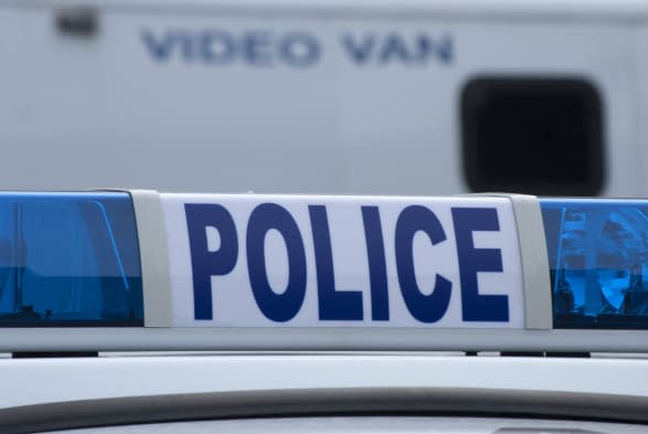 Closeup of police car sign with video unit vehicle in background.