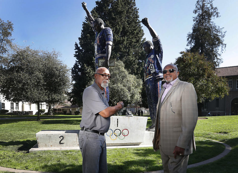 FILE - In this Oct. 17, 2018, file photo, John Carlos, left, and Tommie Smith pose for a photo in front of statue that honors their iconic, black-gloved protest at the 1968 Olympic Games, on the campus of San Jose State University in San Jose, Calif. Smith, Carlos and Gwen Berry are among the more than 150 educators, activists and athletes who signed a letter Thursday, July 22, 2021, urging the IOC not to punish participants who demonstrate at the Tokyo Games. ( (AP Photo/Tony Avelar, File)