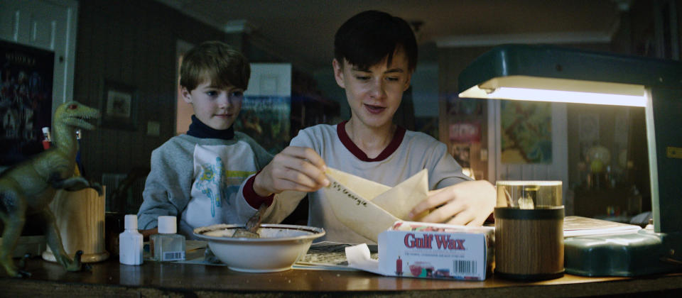 Two boys build a paper boat together