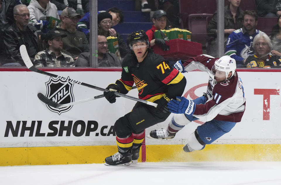 Colorado Avalanche's Andrew Cogliano (11) falls while vying for the puck against Vancouver Canucks' Ethan Bear (74) during the second period of an NHL hockey game Friday, Jan. 20, 2023, in Vancouver, British Columbia. (Darryl Dyck/The Canadian Press via AP)