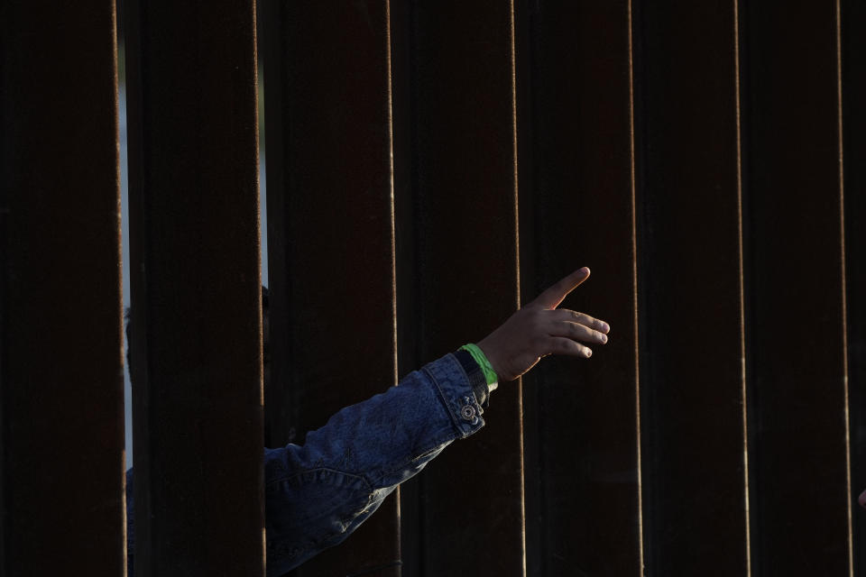 Un hombre señala algo a través de un muro fronterizo el jueves 11 de mayo de 2023, mientras aguarda con otros migrantes entre dos muros para solicitar asilo, en San Diego. Muchos de los cientos de migrantes que esperan entre los muros que separan a la ciudad de Tijuana, México, de San Diego llevan días aguardando para solicitar asilo. Las restricciones al asilo en Estados Unidos implementadas debido a la pandemia de COVID-19, conocidas como Título 42, expiraron el 11 de mayo. (AP Foto/Gregory Bull)