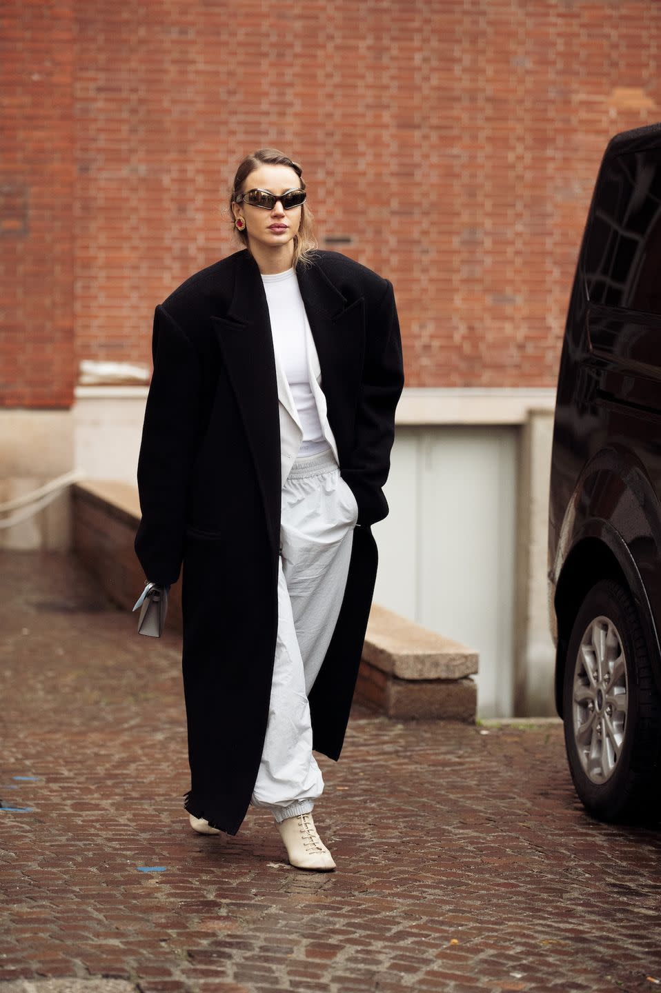 milan, italy february 23 a guest wears white pants, a white top, and a black oversized coat outside sportmax during the milan fashion week womenswear fallwinter 2024 2025 on february 23, 2024 in milan, italy photo by raimonda kulikauskienegetty images