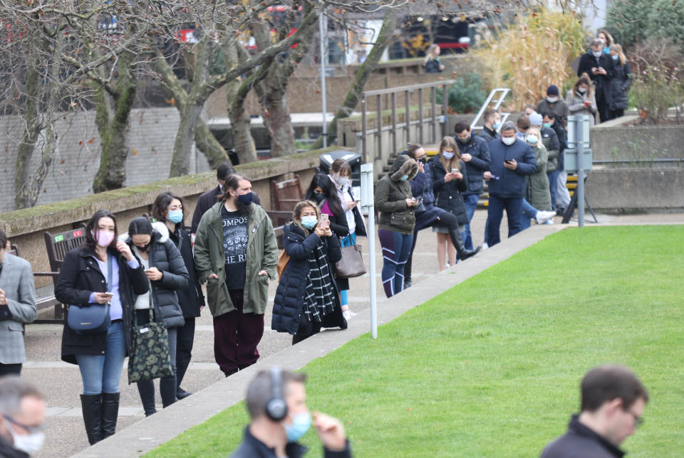 People queue at a vaccination centre at St Thomas' Hospital in London, as the coronavirus booster vaccination programme is ramped up to an unprecedented pace of delivery, with every eligible adult in England being offered a top-up injection by the end of December. Picture date: Tuesday December 14, 2021.