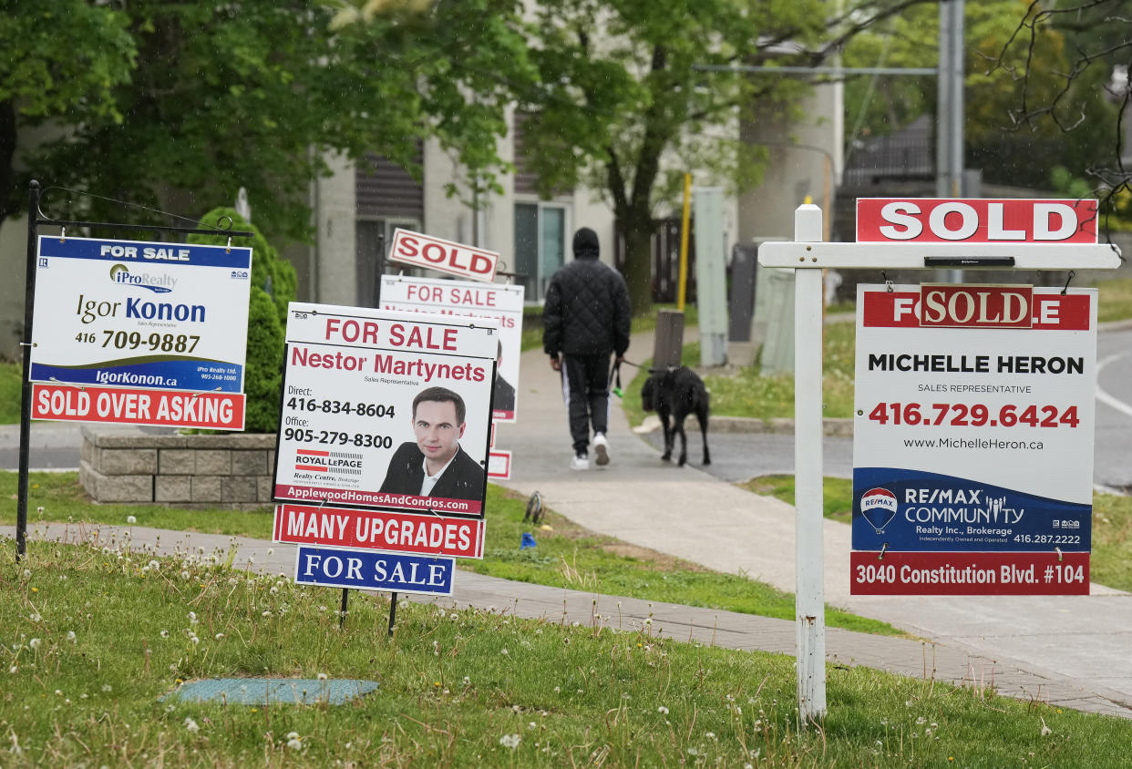 A person walks past multiple for-sale and sold real estate signs for homes in Mississauga, Ont., on Wednesday, May 24, 2023.THE CANADIAN PRESS/Nathan Denette